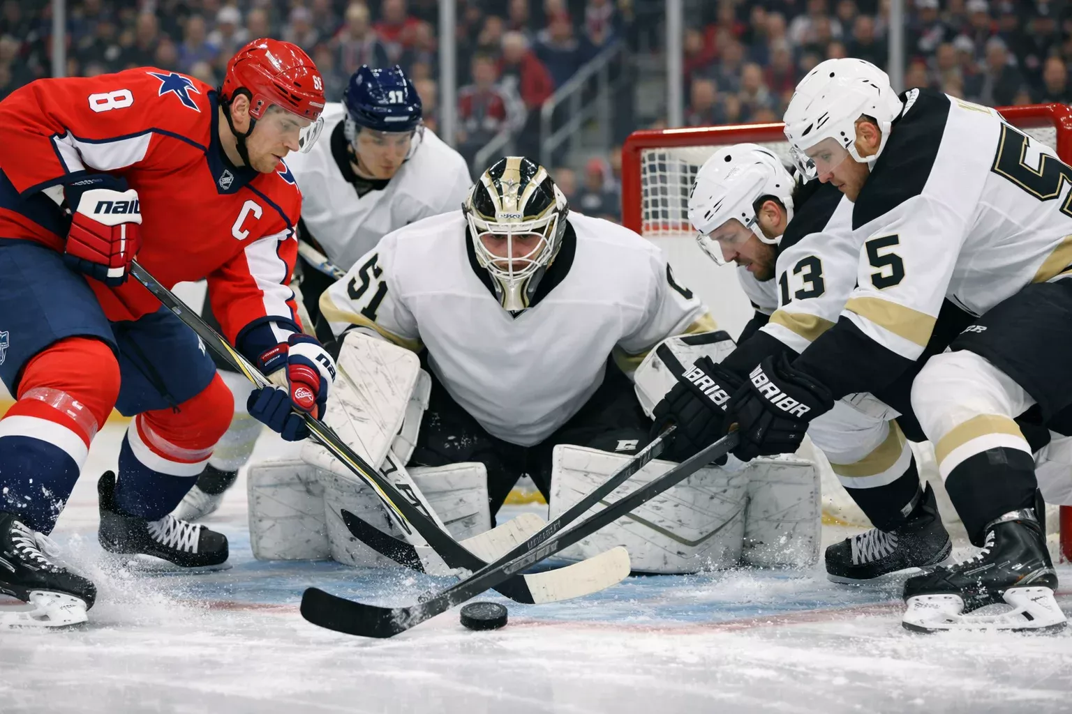 Intense moment during NHL game with players battling for the puck near the goal